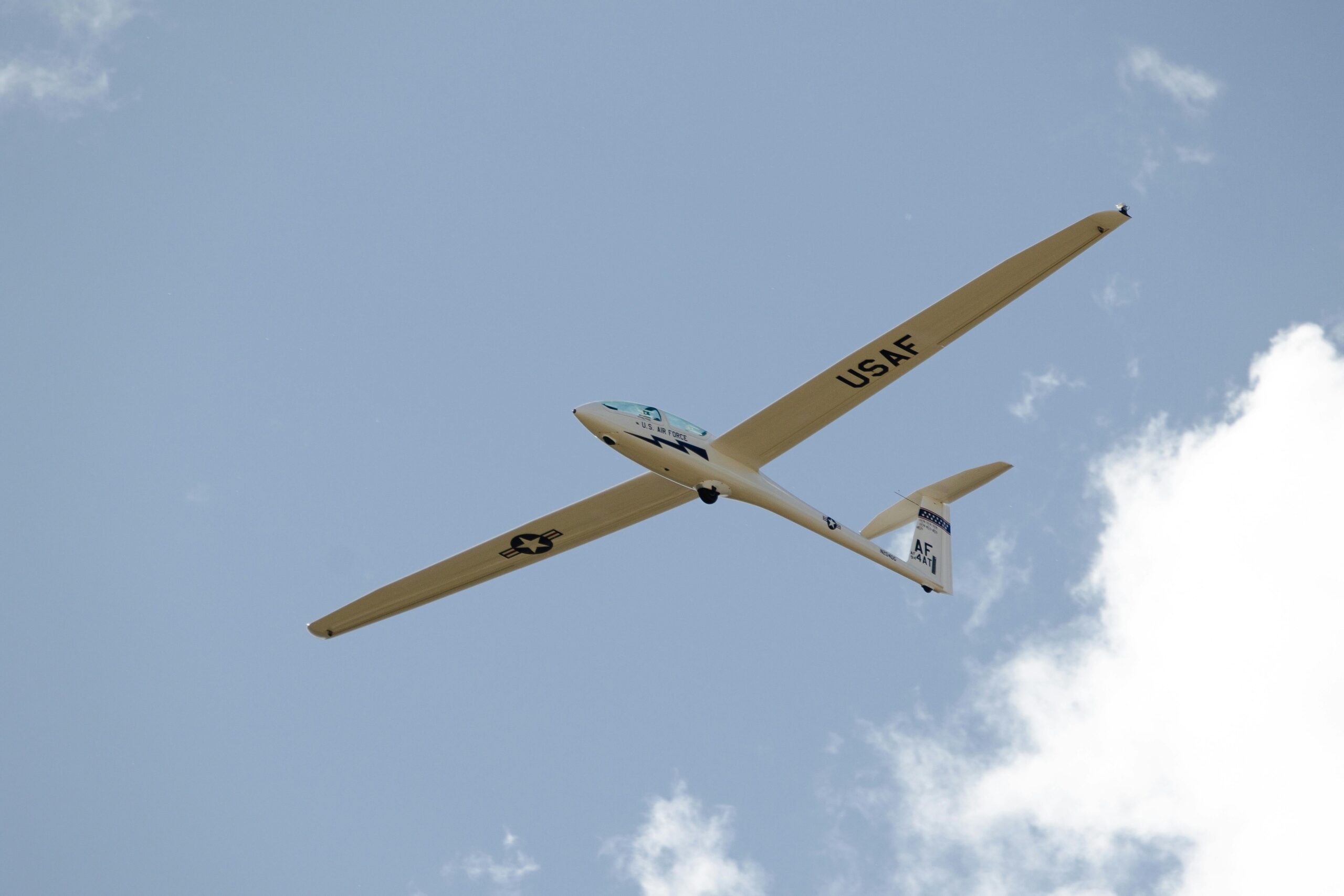 RC glider flying in partly cloudy sky